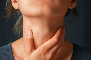 an ent patient touches her throat